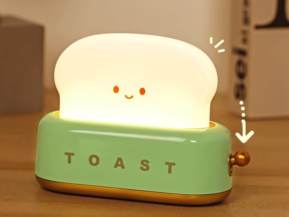 A cute lamp shaped like a toaster with a cute glowing and smiling toast popping from the top.
