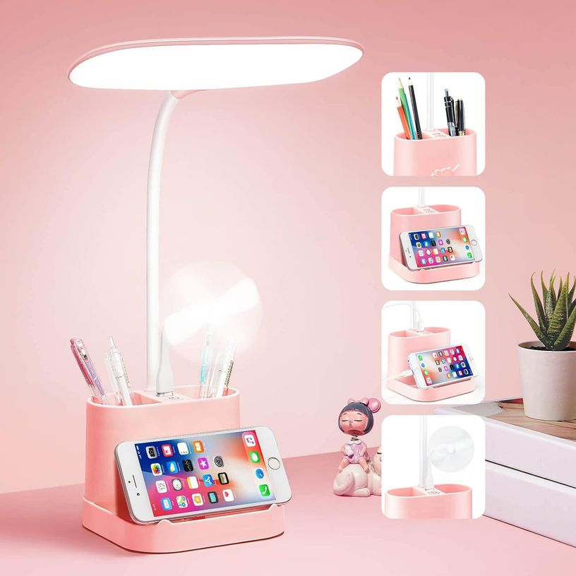 Pink desk lamp with an integrated base for holding a phone and desk supplies like pens.