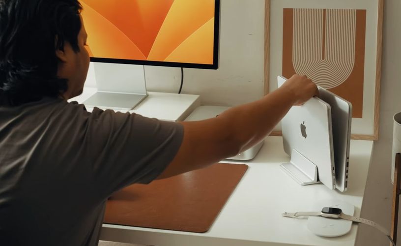 Person placing a macbook into a vertical laptop stand