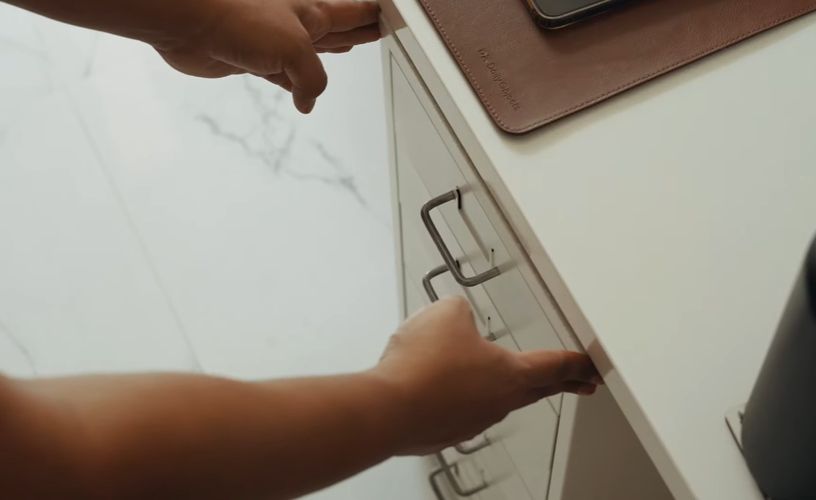 Person pushing a drawer under a table