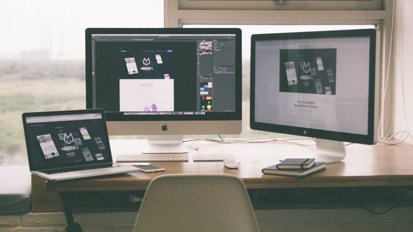 Two monitors and a laptop on a wooden desk